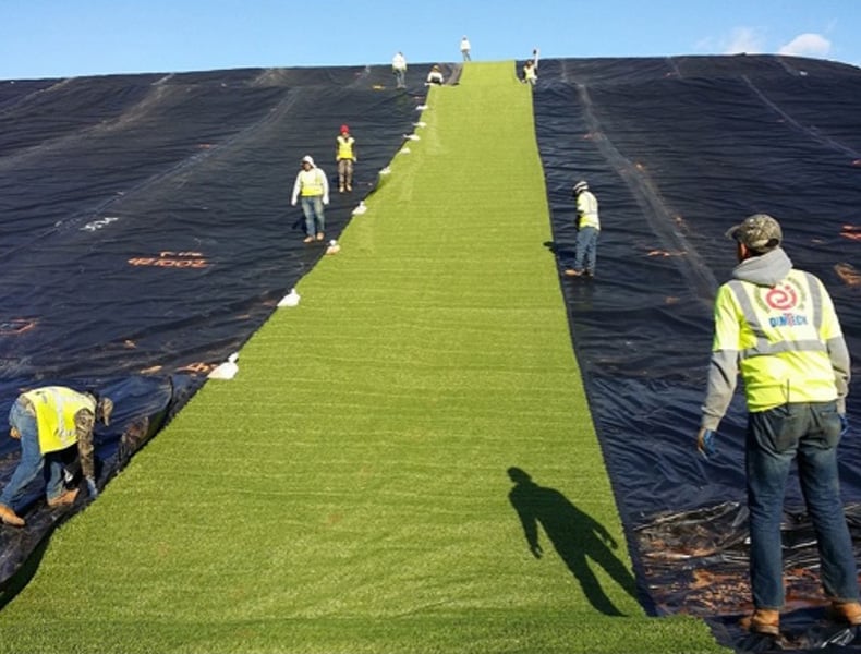 The engineered synthetic turf is rolled out over the Agru Super Gripnet® geomembrane.